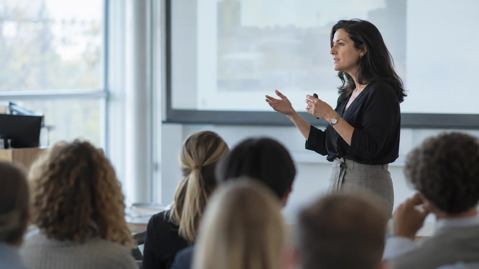 Enseignante en échange avec des auditeurs adultes dans une salle de conférence.